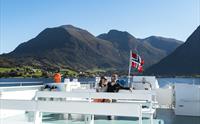 Eit par sit på dekk og nyt den flotte utsikta av Hardangerfjorden og norsk natur.