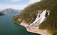Panoramautsikt over Furubergsfossen – Luftfoto som viser Furubergsfossen med fjorden og fjella i bakgrunnen, ein storslått naturarena i Kvinnherad.
