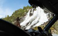 Furubergsfossen sett frå bilen – Utsikt til Furubergsfossen gjennom frontruta, med regnboge som dannar seg i fossen.