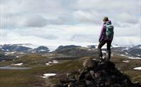 En kvinne som står på en fjelltopp og stirrer mot Hardangerjøkulen.