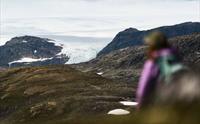 En kvinne i rosa jakke med Hardangerjøkulen i bakgrunnen.