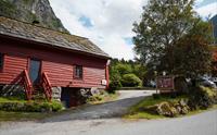 Den raude, tradisjonelle låvebygningen til Olaløo i Bondhus, Hardanger, omgitt av frodig natur og fjell.