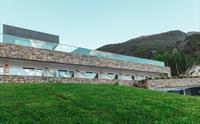 Natursteinmurar på Hardanger House integrert med frodig landskap.