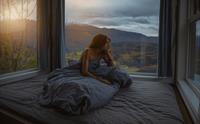 Kvinne slappar av med fjordutsikt frå soverommet i Hardanger Panorama Lodge.