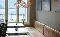 En lang skinnsofa, små bord og stoler på motsatt side.