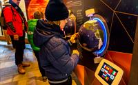 En gutt leker med en av de interaktive utstillingsgjenstandene, en globus i veggen.