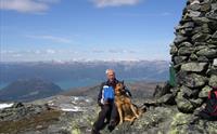 Ein mann og hund ved varden på toppen