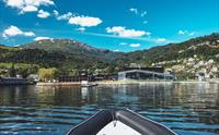 Utsikt mot Hardangerfjord Hotel frå fjorden, med fjell og bygd i bakgrunnen.