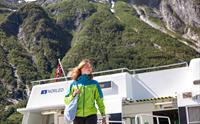 Ung turist går av båten i Eidfjord med flotte fjell i bakgrunnen.