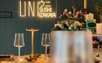 Interiør av UNI Sushi & Izakaya med neon-skilt og blomsterdekorasjoner.